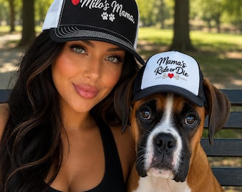 May include: A black and white trucker hat with the text Milo's Mama and a red heart and paw prints, alongside a smaller matching black and white trucker hat featuring the text Mama's Ride or Die with a red heart and a bone graphic.