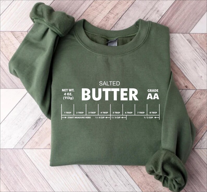 以下が含まれることがあります： バターのさじとカップの測定ガイドと「SALTED BUTTER GRADE AA」のテキストが書かれた緑色のスウェットシャツ。「NET WT. 4 OZ. (113g)」のテキストも含まれています。