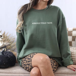 Puede incluir: Una sudadera verde con el texto "ABSOLUTELY NOT." en letras blancas. La sudadera se lleva sobre un pantal&oacute;n corto de estampado de leopardo.