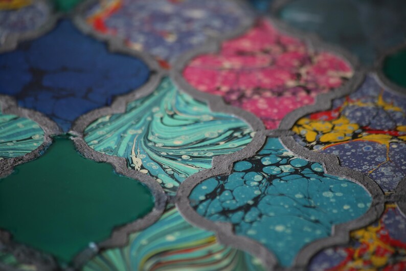 May include: Close-up of a colorful patterned surface with a geometric design. The surface is made up of different colored sections, each with a unique marbled pattern. The colors include blue, green, pink, and yellow.