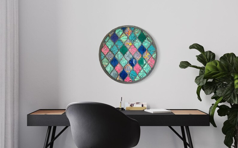 May include: A round wall decor with a mosaic design featuring a repeating pattern of teal, blue, pink, and green diamond shapes. The mosaic is set in a silver frame.