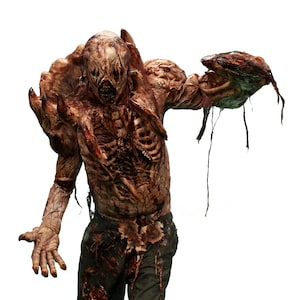 May include: A gruesome, decaying creature with exposed ribs and torn flesh. The figure is wearing dark pants and has a grotesque, distorted face. The creature's arm is outstretched, holding a mass of decaying matter.