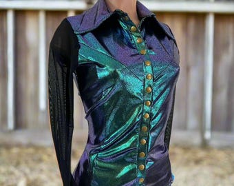 May include: Iridescent button-down shirt with a shimmering teal and purple finish. Features gold-colored buttons and black mesh sleeves. The shirt is displayed on a mannequin, paired with blue jeans.