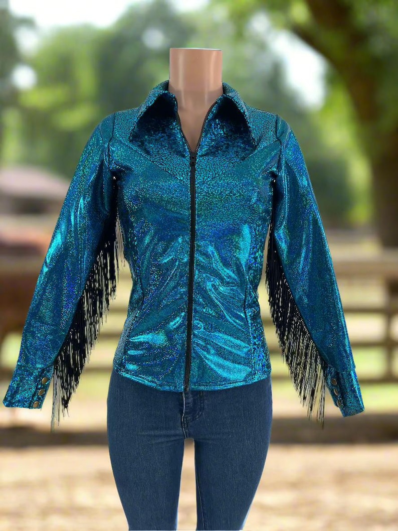 Puede incluir: Una chaqueta azul turquesa con flecos negros en las mangas y una cremallera negra. La chaqueta tiene un acabado brillante e iridiscente.