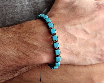 May include: A turquoise blue beaded bracelet with a brown cord. The bracelet is made of square beads and has a simple design.