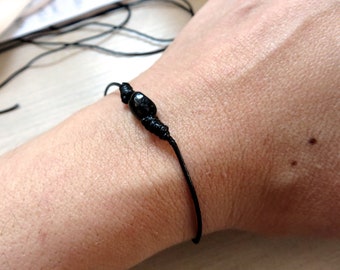 May include: A black string bracelet with a black bead.