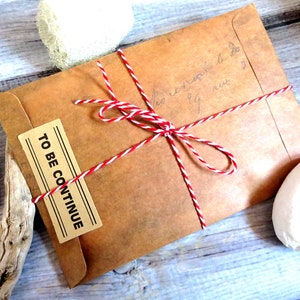 May include: A brown paper envelope tied with red and white twine. The envelope has a label that says "TO BE CONTINUE".