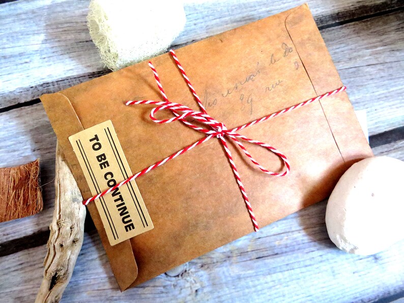 May include: A brown paper envelope tied with red and white twine. The envelope has a label that says "TO BE CONTINUE".