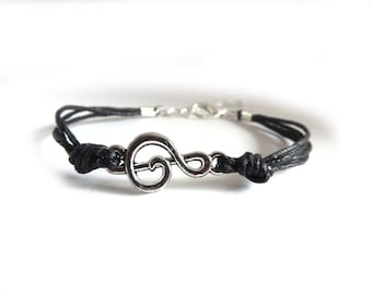 May include: Black braided cord bracelet with a silver treble clef charm.