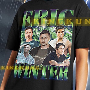 May include: Black unisex t-shirt with a graphic print of a group of men with the text "ERIC WINTER" on it. The shirt is being modeled by a person wearing black pants.