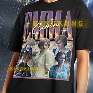 May include: Black t-shirt with a graphic print of a collage of images of a woman. The text "Emma Coming" is printed in purple and yellow on the shirt.