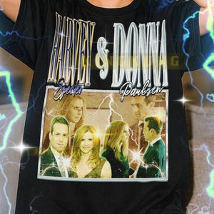 May include: Black t-shirt featuring the text "Harvey & Donna Specter Paulsen" in a vintage style. The shirt includes a framed image of people. The model is wearing a XL shirt. This unisex shirt fits true to size.
