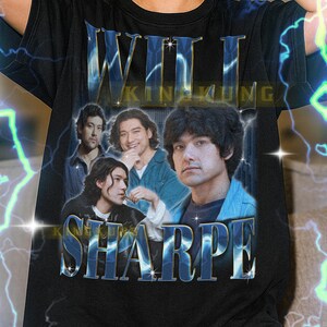 Peut inclure: T-shirt noir avec l'inscription "WILL KING KUNG SHARPE" en bleu métallisé. Le t-shirt présente un graphisme de quatre hommes dans un style vintage. Le t-shirt est de coupe unisexe.