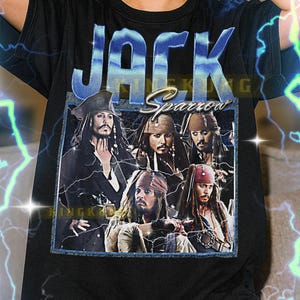 Puede incluir: Camiseta negra con un gráfico de Jack Sparrow de las películas de Piratas del Caribe. El diseño incluye el nombre "JACK Sparrow" en una fuente azul y plateada, con múltiples imágenes del personaje.