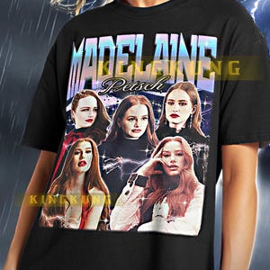 Puede incluir: Camiseta negra con un estampado gráfico de un grupo de mujeres con el texto "MADELAINE Petsch" encima. El gráfico está en un estilo retro con un diseño de rayo.