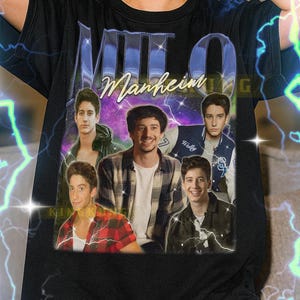 May include: Black unisex t-shirt with a graphic of Milo Manheim and the text "Manheim". The design includes multiple images of the actor. The shirt has a crew neck and short sleeves.