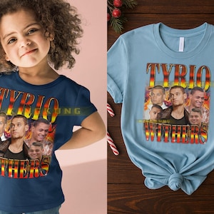 May include: A navy blue t-shirt and a light blue t-shirt featuring a graphic design. The design includes the name "TYRIO WITHERS" in a stylized font, along with multiple images of a person. The shirts are short-sleeved.