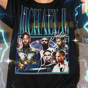 May include: Black t-shirt with a graphic of Michael B. Jordan and the text "MICHAEL B. JORDAN" in blue and teal. The design has a vintage aesthetic.