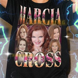 Puede incluir: Camiseta unisex negra con el nombre "MARCIA CROSS" en un estilo retro. El diseño incluye múltiples imágenes de Marcia Cross. El texto en la parte inferior de la camiseta no está incluido en la descripción.