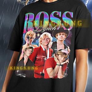 May include: Black t-shirt featuring a graphic of Ross Lynch with the text "ROSS Lynch" in a colorful, retro font. The shirt has a vintage aesthetic with multiple images of Lynch. The brand name "KINGKUNG" is also visible.