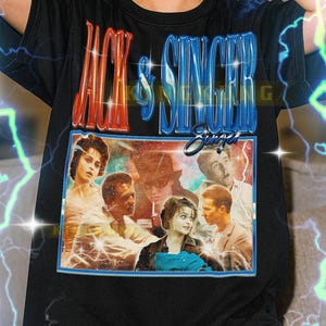 May include: Black t-shirt featuring the text "JACK & SINGER" in red and blue, with a vintage-style image of actors. The shirt has a crew neck and short sleeves. The text "Singer" is in a cursive font.