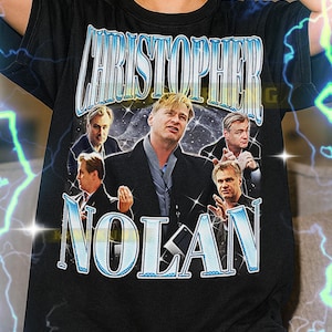 Könnte beinhalten: Schwarzes T-Shirt mit einem Retro-Grafik von Christopher Nolan und dem Text "CHRISTOPHER NOLAN". Das Design beinhaltet mehrere Bilder von Nolan. Das T-Shirt ist unisex.