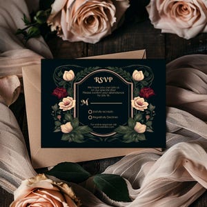 May include: A black RSVP card with a floral design featuring red and cream roses. The card has a gold border and the text "RSVP" in a gold font. The text reads "We hope you can join us on our special day! Please confirm your attendance by July 1st. M Joyfully accepts Regretfully Declines For online response visit www.website.com"