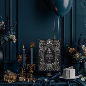 May include: A black and white invitation card with an ornate design featuring a snarling beast's head. The text reads "The Beast Awakens" and "30th Birthday". The card is displayed on a black stand against a dark blue background.