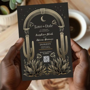 Può includere: Carta di salvataggio della data nera con accenti dorati. La carta presenta un arco stilizzato con una luna crescente, cactus e fiori. Il testo recita "Save the Date" per celebrare il matrimonio di Josephine Black e Adrian Hermosa il 24.08.2053 a Moon Villa, 12345 Darton. Un codice QR è incluso per l'invito formale.