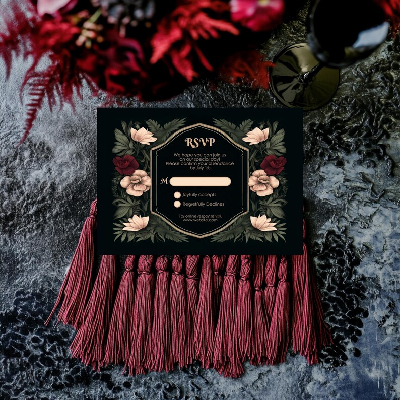 May include: Black RSVP card with gold trim and floral design. The card has a tassel border and the text "RSVP" in gold lettering. The text reads "We hope you can join us on our special day. Please confirm your attendance by July [blank space]" with two options: "joyfully accepts" and "Regretfully Declines". The card also includes the text "For online response visit www.website.com".