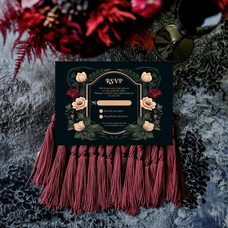 May include: A black RSVP card with gold accents and floral designs. The card has a section for guests to confirm their attendance to a wedding. The text on the card reads "RSVP, We hope you can join us on our special day! Please confirm your attendance by July [blank space]".