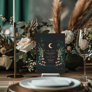 May include: A black wedding invitation with gold lettering and a crescent moon design. The invitation features a floral border with green leaves and pink flowers. The text on the invitation reads "Celene & Ryan" and includes the date and time of the wedding.