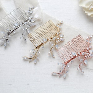 May include: Three decorative hair combs in silver, gold, and rose gold. Each comb features a delicate design of leaves and crystals. The combs are arranged on a white surface with a soft, flowing fabric.