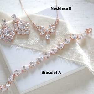 May include: A set of rose gold jewelry featuring a necklace, bracelet, and earrings. The necklace and earrings have a floral design with clear cubic zirconia stones. The bracelet has a simple design with clear cubic zirconia stones.