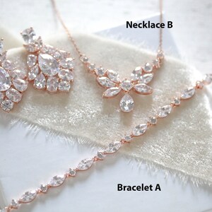 May include: A set of rose gold jewelry with clear cubic zirconia stones. The set includes a necklace, bracelet, and earrings. The necklace is labeled "Necklace B", the bracelet is labeled "Bracelet A", and the earrings are labeled "SET C".