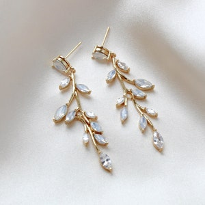 May include: A pair of gold dangle earrings with a delicate branch design and clear crystal accents.