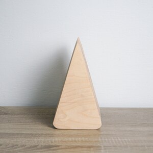 May include: A light wood triangular shaped geometric ornament. The ornament is made of wood and has a smooth, natural finish.