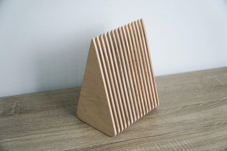 May include: A wooden triangular stand made of thin, stacked slats. The stand is made of light wood and has a natural finish.