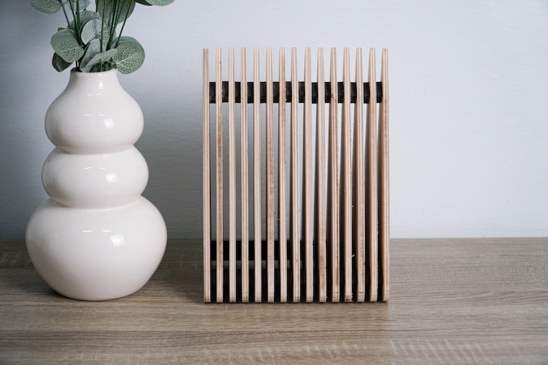 May include: A wooden slatted decorative object with a natural wood finish. The object is standing on a light brown surface.