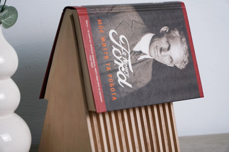 May include: A wooden book stand with a red and black book titled "Henry Ford, My Life and Work".