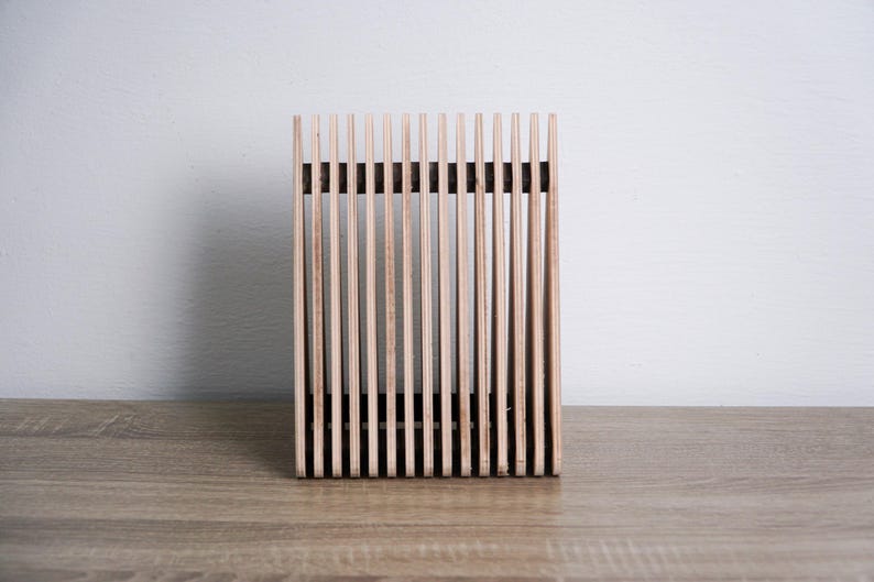 May include: A wooden magazine rack with a slatted design. The rack is made of natural wood and has a rectangular shape.