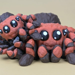 May include: Two 3D-printed toy spiders. The spiders are red and brown with large, black and white eyes. The legs and body are a mix of red and brown. The spiders are posed together, creating a playful scene.