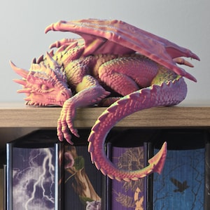 May include: A sleeping dragon figurine with iridescent scales that shift between shades of pink, purple, and yellow. The creature features detailed wings, sharp claws, and a long, curved tail that hangs over the edge of a shelf.
