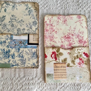 May include: Two decorative paper envelopes with floral patterns. The top envelope has a blue and white floral pattern. The bottom envelope has a pink and white floral pattern. Both envelopes have a scalloped edge.