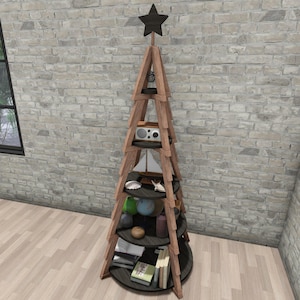 Könnte beinhalten: Ein baumförmiges Holzregal mit mehreren kreisförmigen Regalböden. Die Regale sind mit dekorativen Gegenständen wie einem kleinen Radio, einem Modellsegelschiff, Muscheln und Büchern gefüllt. Ein schwarzer Stern krönt die Struktur. Das Regal ist aus hellbraunem Holz gefertigt.