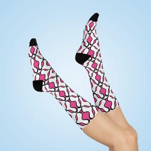 May include: A pair of white knee-high socks with a pink and black abstract pattern.