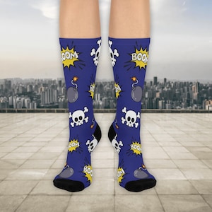May include: Blue socks with a repeating pattern of white skulls, gray bombs, and yellow "BOOM" text. The socks have black heels and toes, and are knee-high.