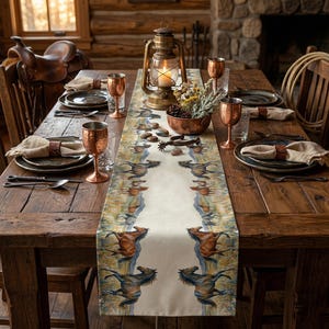 May include: A rustic dining table set for a meal, featuring a cream-colored table runner with a horse design. The table is set with copper-colored goblets, plates, and napkins. A lantern and a bowl of flowers are in the center.