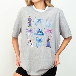 a woman wearing a gray shirt with disney characters on it