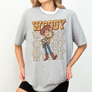 a woman wearing a woody t - shirt and shorts